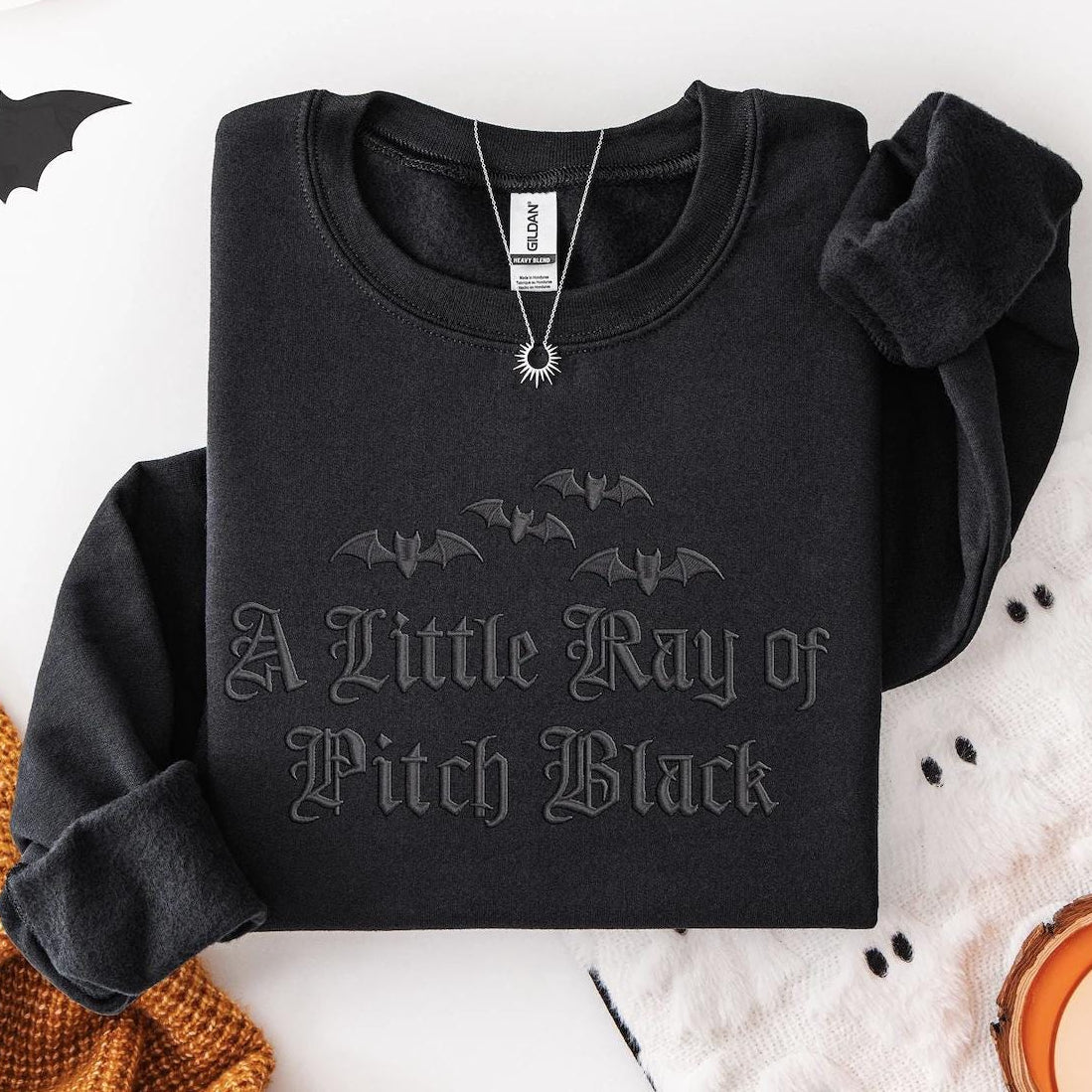 Black sweatshirt with bat design and text on a Halloween-themed background