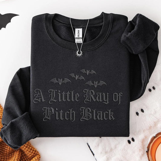 Black sweatshirt with bat design and text on a Halloween-themed background
